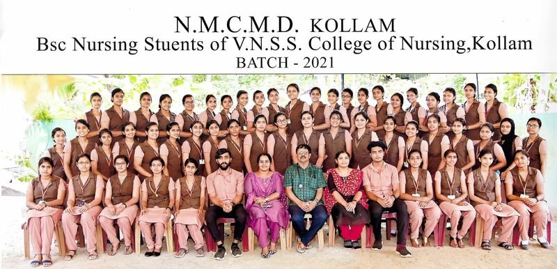 Group photo of BSc nursing students in brown and pink uniforms with Dr. Nicholas Christy seated in the centre